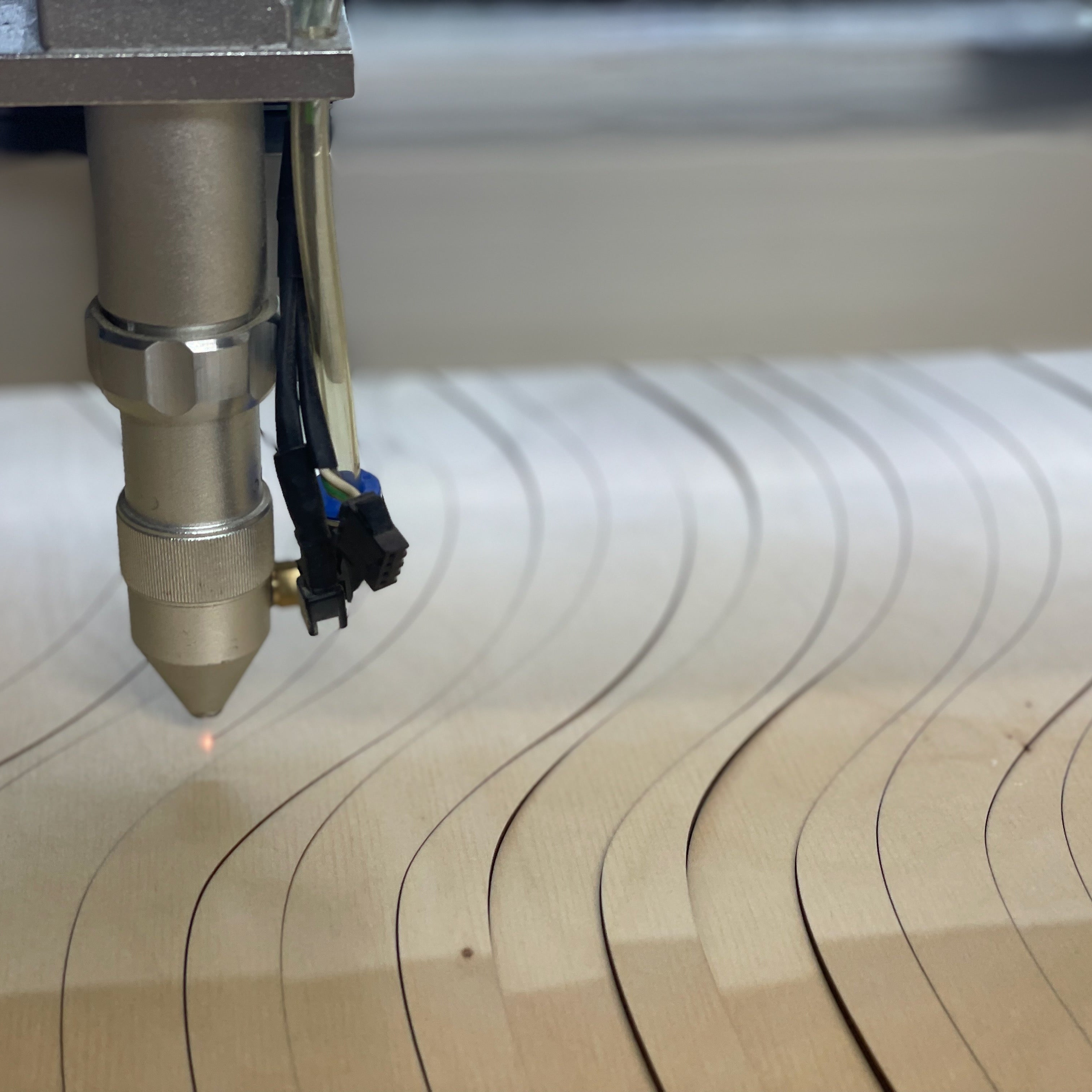 CNC machine cutting a wavy pattern into a wooden board