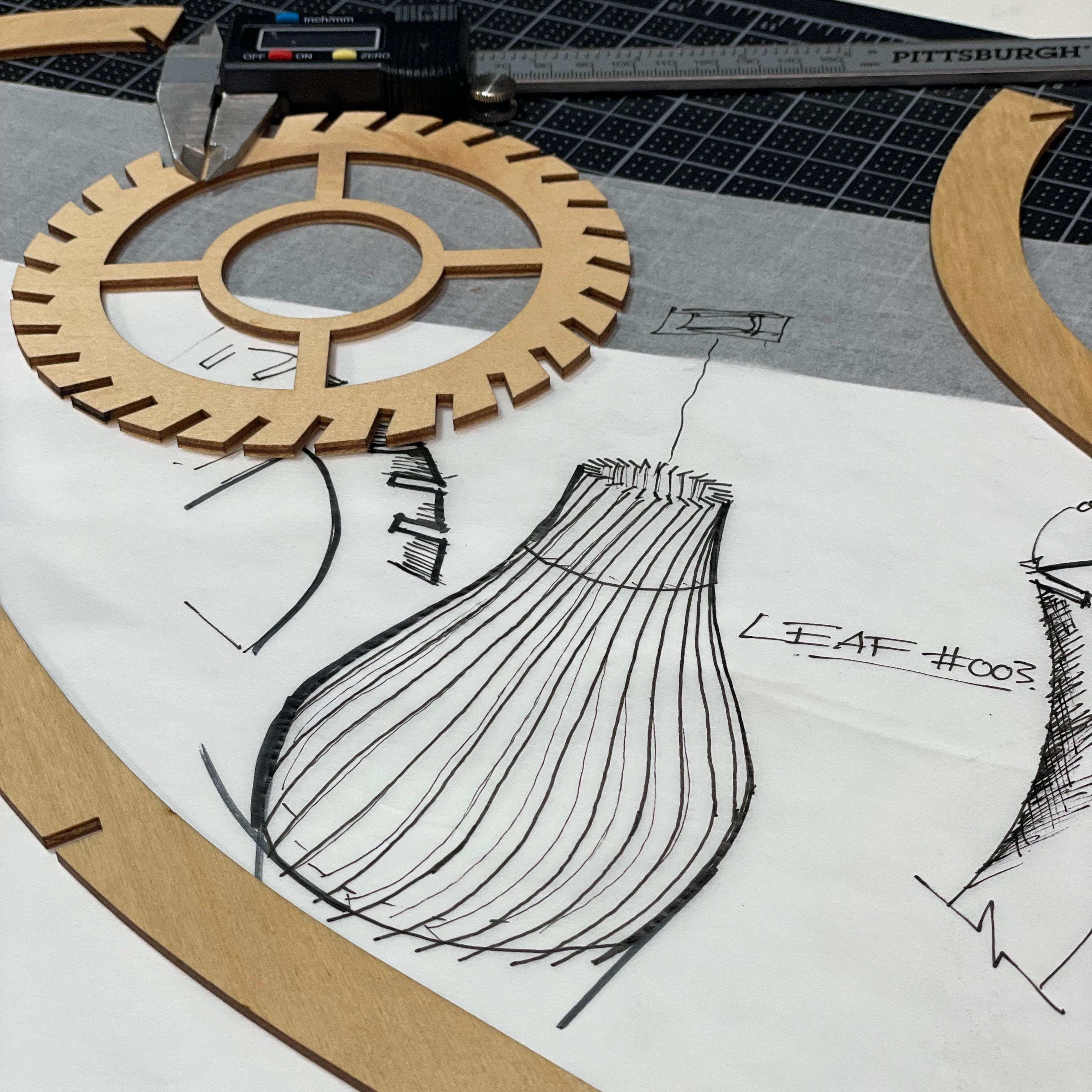 Wooden gear model on a table with technical drawings and measurements.