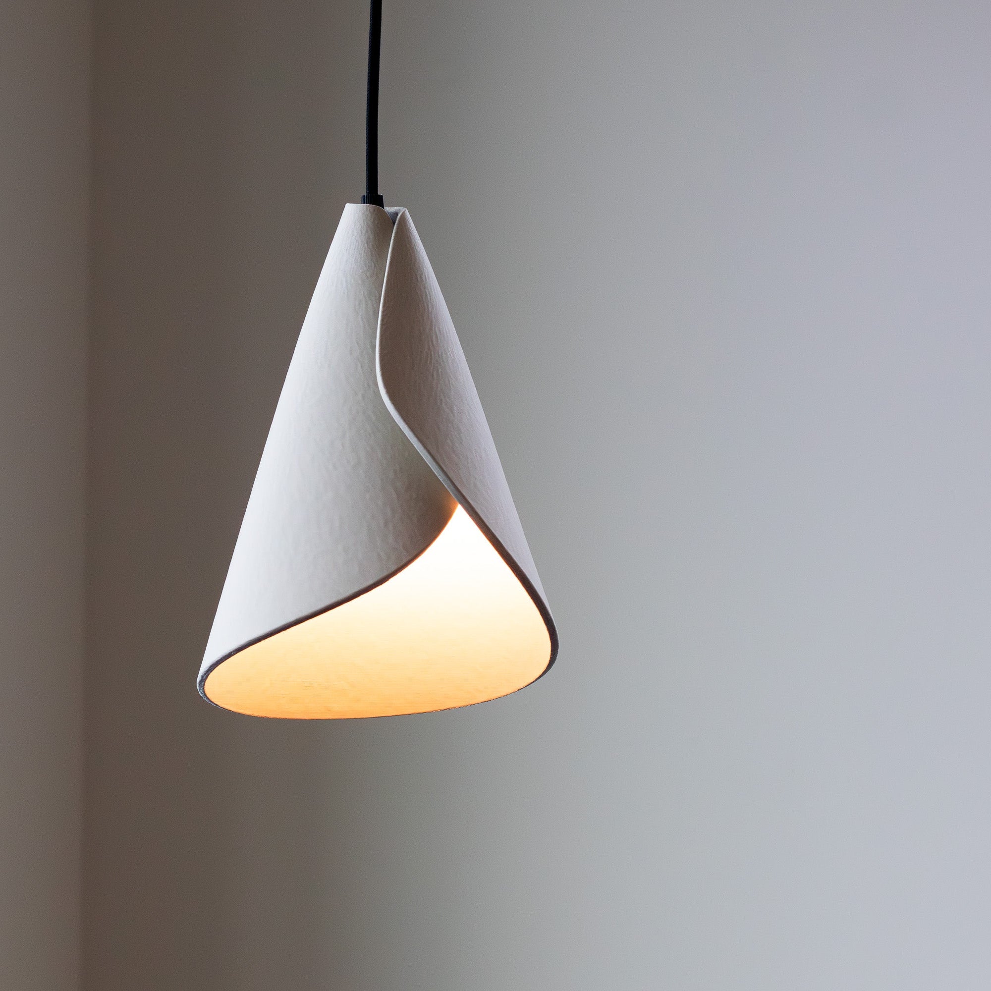 Modern pendant light with a white cone-shaped shade on a neutral background