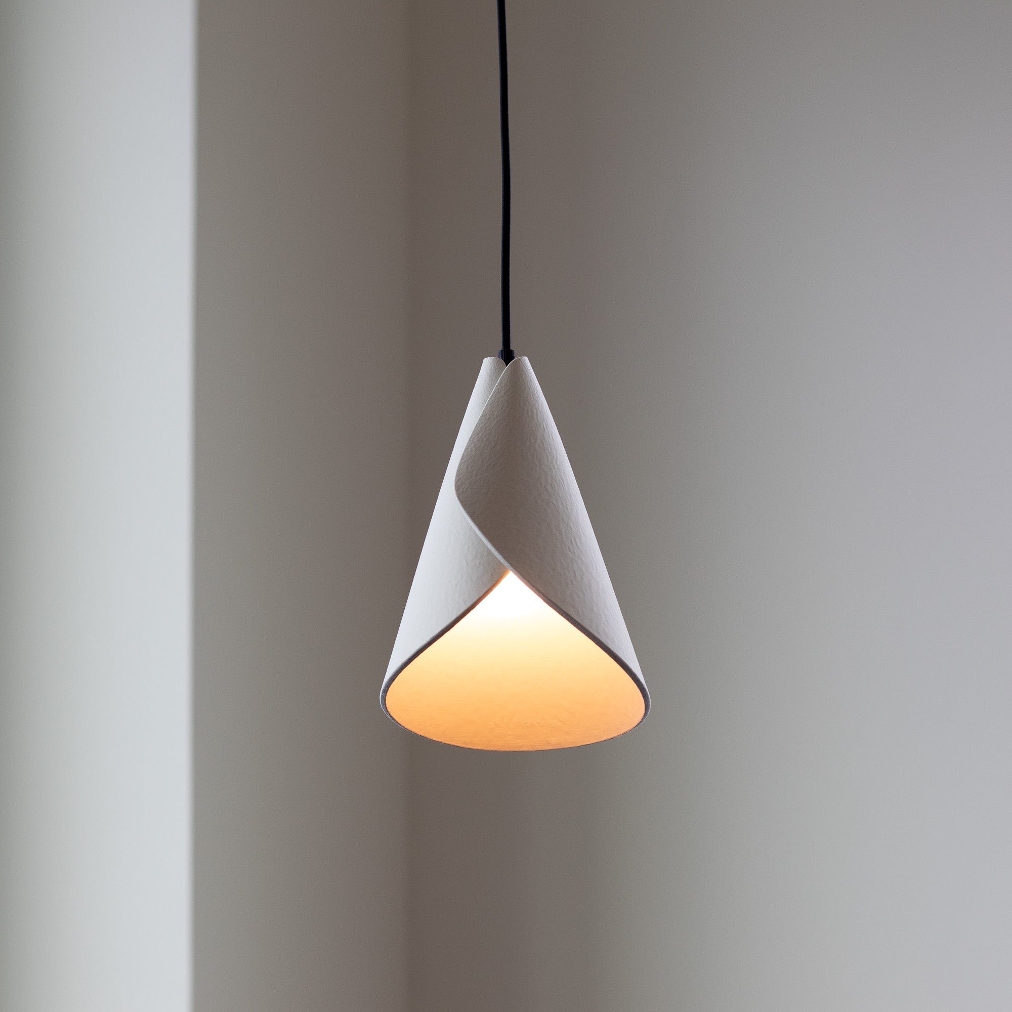 Modern pendant light with a white shade and warm glow on a neutral background