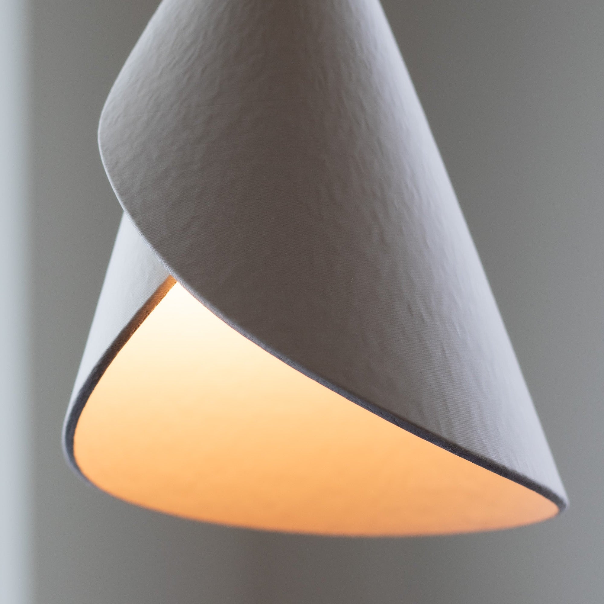 Gray cone-shaped lamp with a warm glow on a gray background